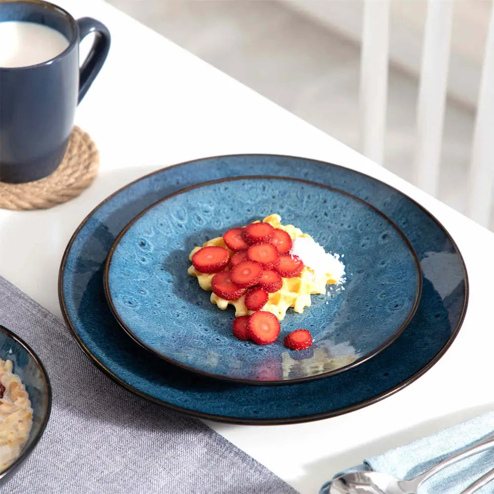 Blå rund keramik middags- och desserttallrik med våffla, jordgubbar och florsocker