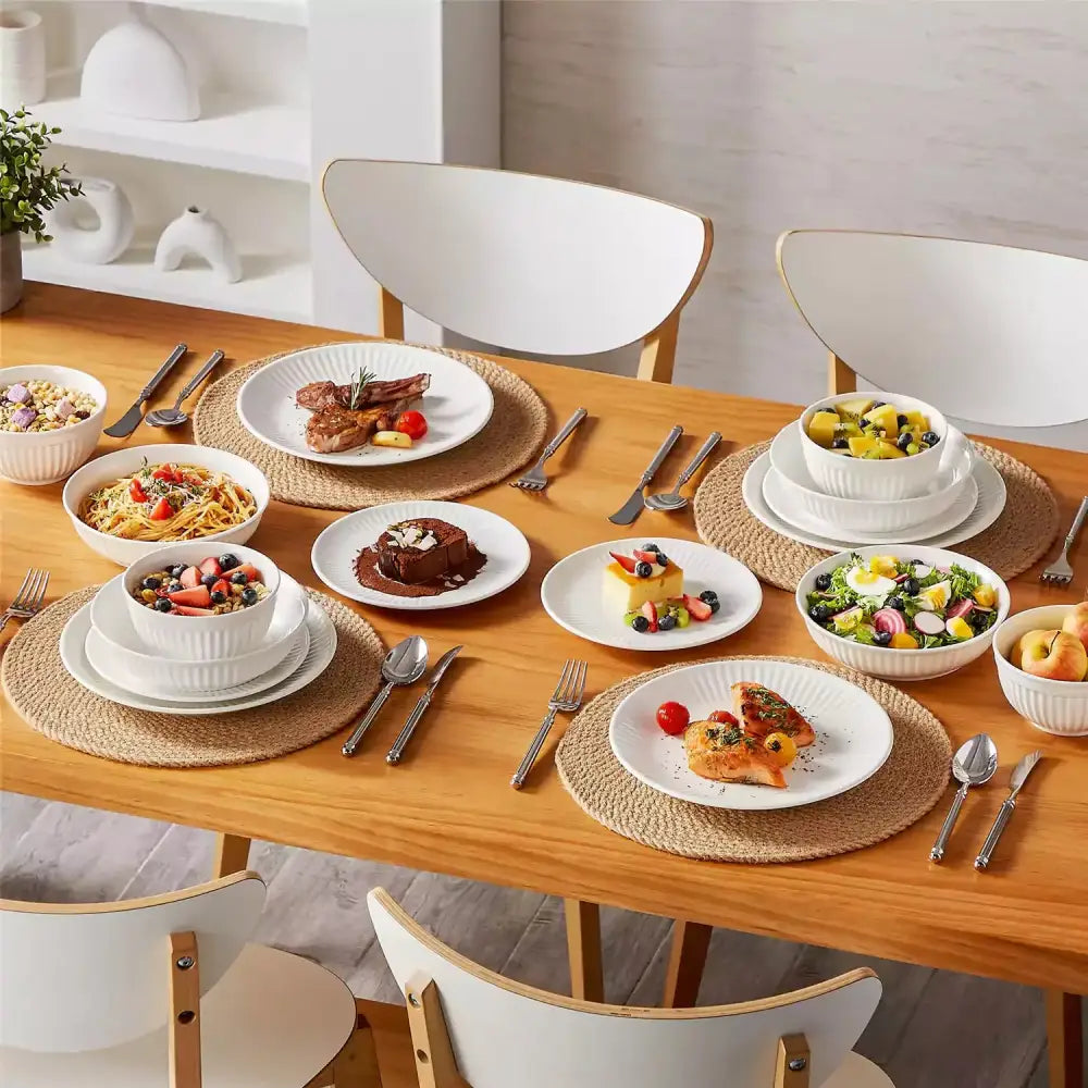 Fullt dukat bord med vita tallrikar, mat och bestick för LEYLA - Servis - 16 delar