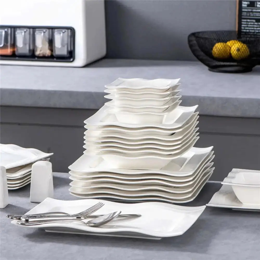 En hög av vit porslinservis med vågiga kanter från MARIA - Servis - 28 delar