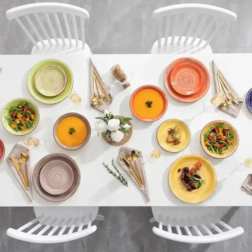 Fullt dukat bord med färgglada tallrikar, skålar och guldbestick för SAVIERO 18 delar
