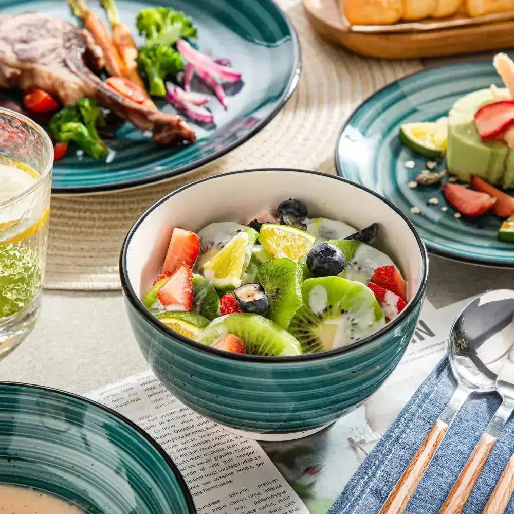 Teal keramisk skål med vit kant fylld med färgglad fruktsallad från THEO Servis 24 delar
